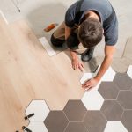 Overhead view of a man installing hexagonal tile flooring.