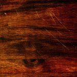Dark chestnut hardwood flooring with scratches in it