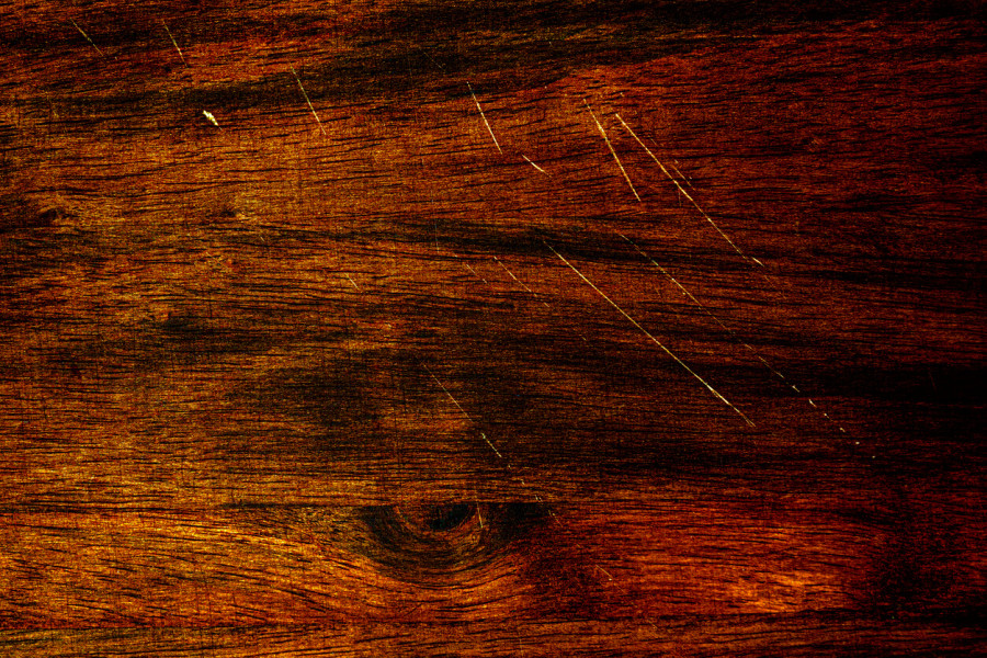 Dark chestnut hardwood flooring with scratches in it